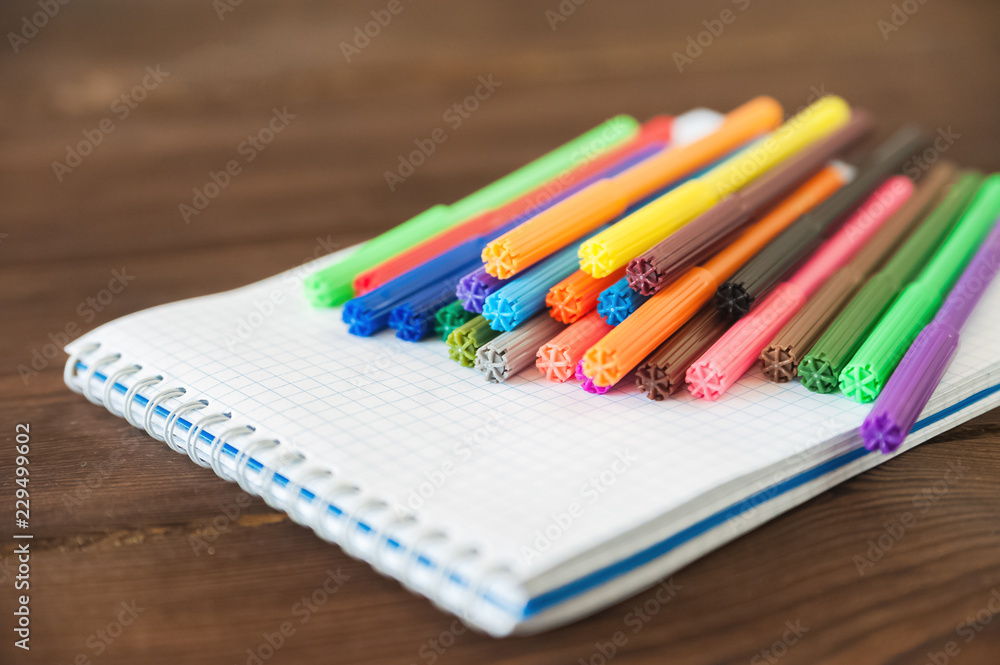 Multicolored felt pens with notebook on wooden background. Recreation concept drawing Multicolored felt pens with notebook on wooden background. Recreation concept drawing