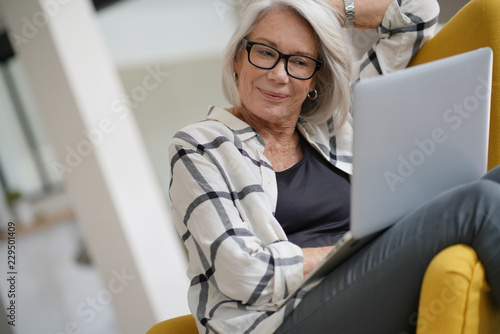  Relaxed modern senior woman at home on computer
