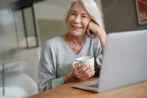  Elderly woman at home with computer
