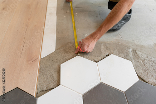 Male worker installing new wooden laminate flooring on a warm film floor. infrared floor heating system under laminate floor