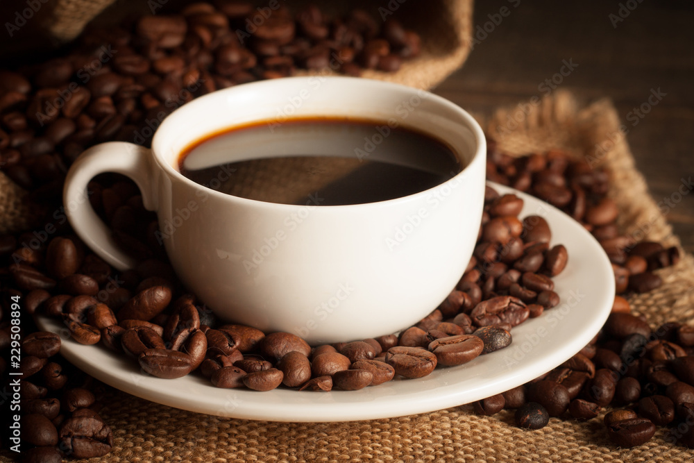 Coffee cup and beans on a rustic background. Coffee Espresso and a piece of cake with a curl. Cup of Coffee and coffee beans on table. Coffee cup and beans on a rustic background. Coffee Espresso and a piece of cake with a curl. Cup of Coffee and coffee beans on table.
