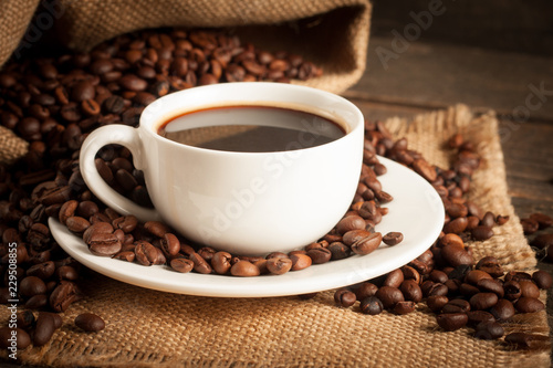 Coffee cup and beans on a rustic background. Coffee Espresso and a piece of cake with a curl. Cup of Coffee and coffee beans on table. © xander21