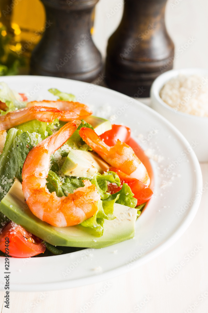Fresh Caesar shrimp salad with delicious prawns, ruccola, spinach, cabbage, arugula, egg, parmesan and cherry tomato on wooden background. Oil, salt and pepper. Healthy and diet food concept. Fresh Caesar shrimp salad with delicious prawns, ruccola, spinach, cabbage, arugula, egg, parmesan and cherry tomato on wooden background. Oil, salt and pepper. Healthy and diet food concept.
