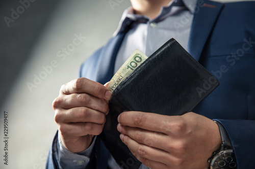 Elegant man in suit pulls out his money from wallet. Conception of money management.