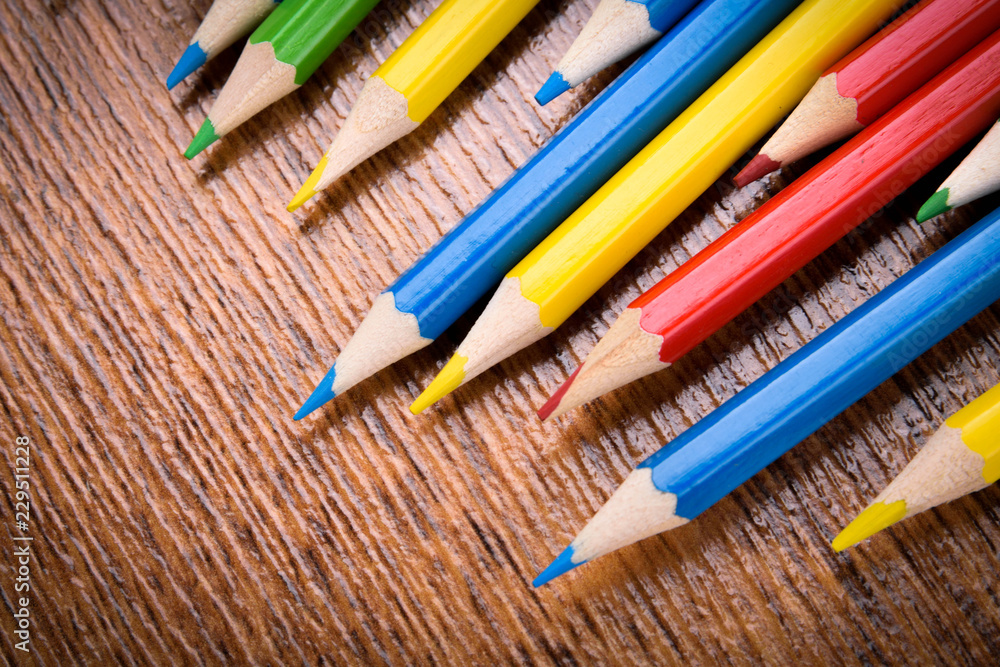 Different colored pencils on the brown wooden table background .Top view .Close up .Color .Pencil.Set Different colored pencils on the brown wooden table background .Top view .Close up .Color .Pencil.Set
