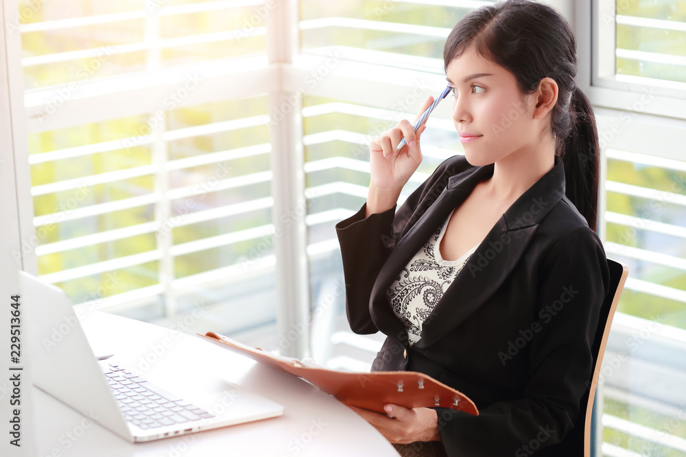 businesswoman thinking of something with notebook with laptop computer businesswoman thinking of something with notebook with laptop computer