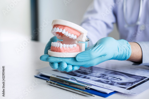 Male doctor or dentist working with patient tooth x-ray film, model and equipment used in the treatment and analysis teeth disease of dental and dentistry at workplace