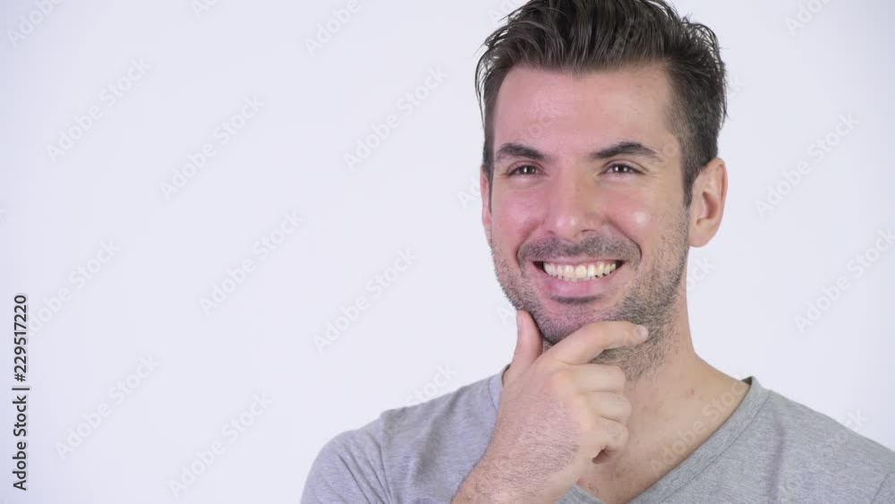 Young happy Hispanic man smiling and thinking Young happy Hispanic man smiling and thinking