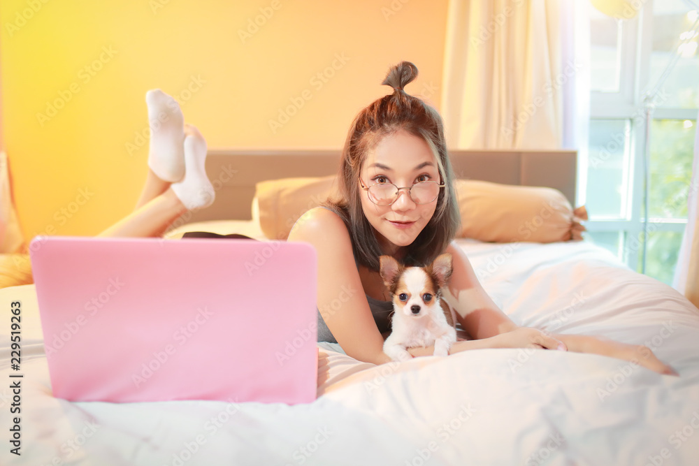 beautiful and sexy woman using cell phone and playing with cute puppy dog on bed beautiful and sexy woman using cell phone and playing with cute puppy dog on bed