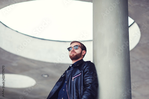 Handsome young man posing in fashion sunglasses and leather jacket