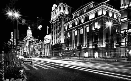night lights and long exposure stripes of moving cars on the streets of shanghai with old architecture in Bund, China