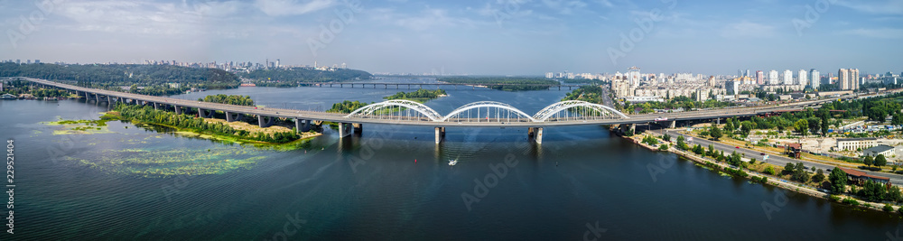 Aerial panorama view of automobile and railroad Darnitsky bridge across Dnieper river from above, Kiev city skyline