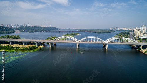 Aerial top view of automobile and railroad Darnitsky bridge across Dnieper river from above, Kiev city skyline photo