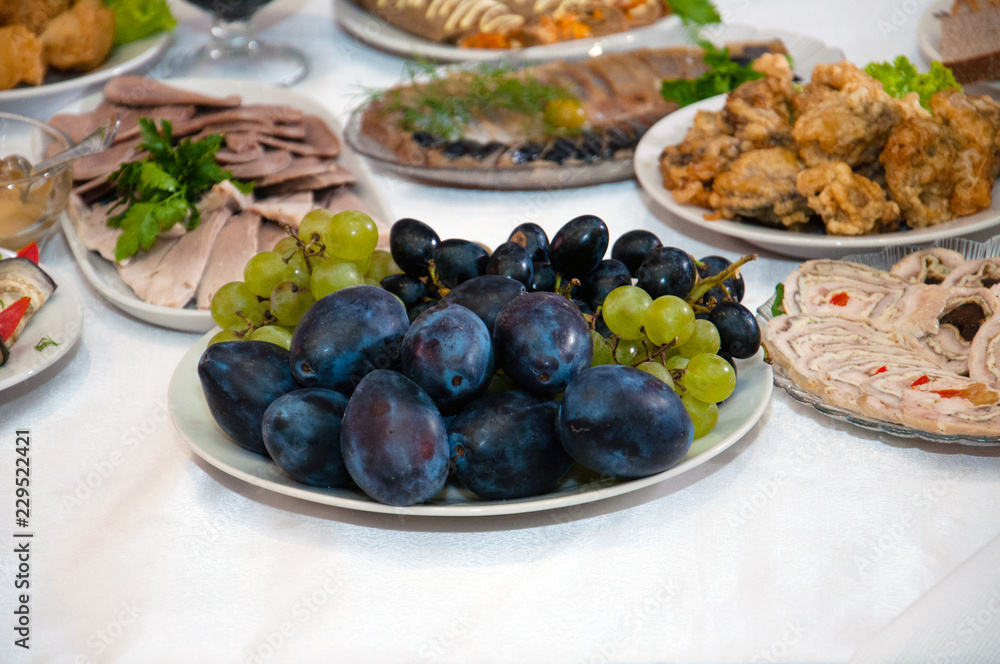 Plum fruits, grapes, meat, fish and roll on a festive New Year's table