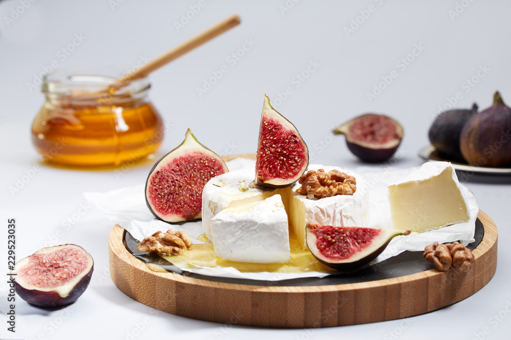 Camembert cheese on wrapping paper with figs, nuts and honey
