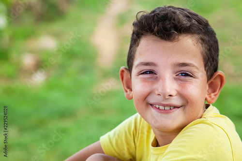 Portrait of happy smiling child boy outdoors. Concept of happy family or successful adoption or parenting.