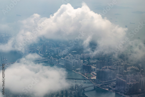 Aerial view of big city through clouds, Hong Kong general view from airplane.