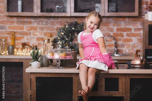 Little cute girl in the kitchen eating cupcakes