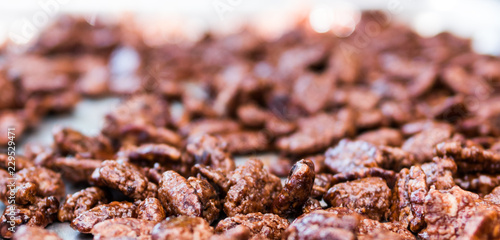 Close up of fresh sugar glazed cinnamon roasted pecans on a metal cookie sheet.