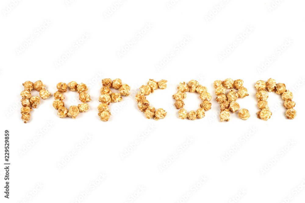 The word POPKORN is laid out from pieces of caramel popcorn on a white background. The word POPKORN is laid out from pieces of caramel popcorn on a white background.
