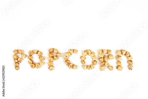 The word POPKORN is laid out from pieces of caramel popcorn on a white background.