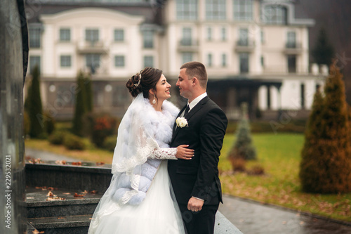 Groom and bride walking in the park on their wedding day. Autumn weather. Rair. Couple umbrella photo