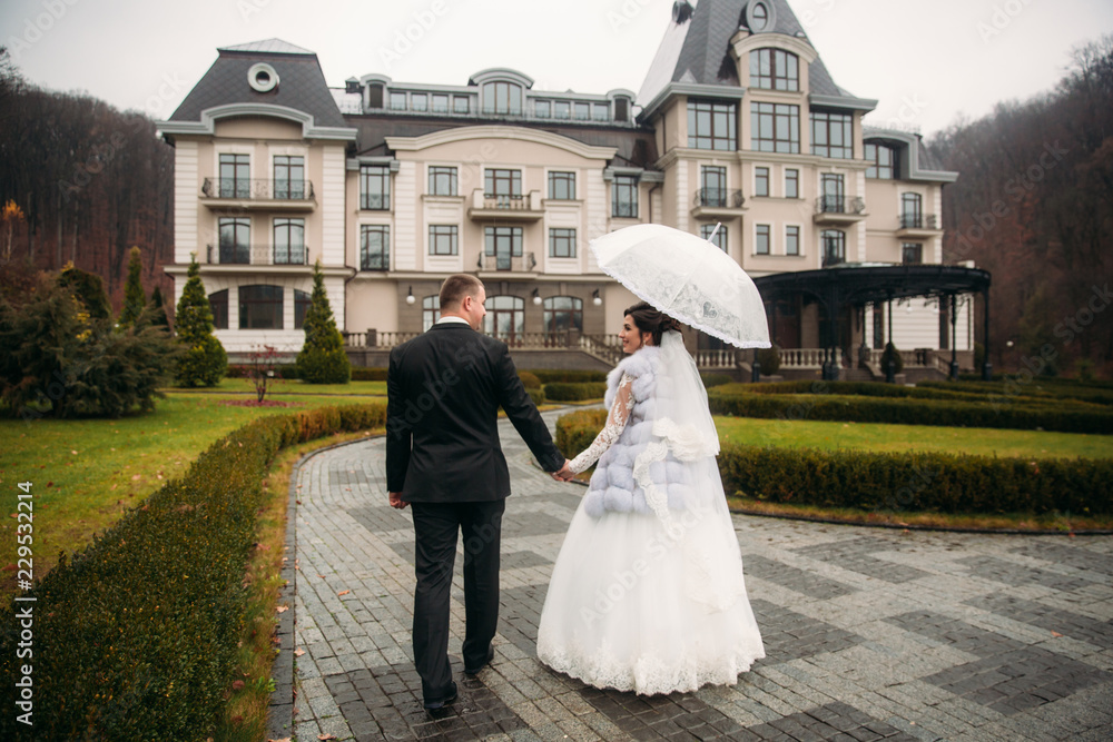 Groom and bride walking in the park on their wedding day. Autumn weather. Rair. Couple umbrella Groom and bride walking in the park on their wedding day. Autumn weather. Rair. Couple umbrella
