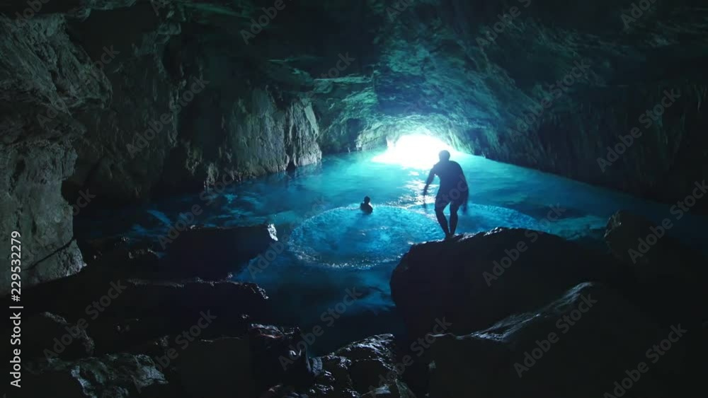 Vidéo Stock Three man jumping in the water inside a blue cave in the