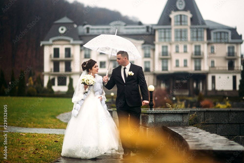 Happy couple walking in their wedding day. Big park with big castle. Autumn weather and colorfull background Happy couple walking in their wedding day. Big park with big castle. Autumn weather and colorfull background