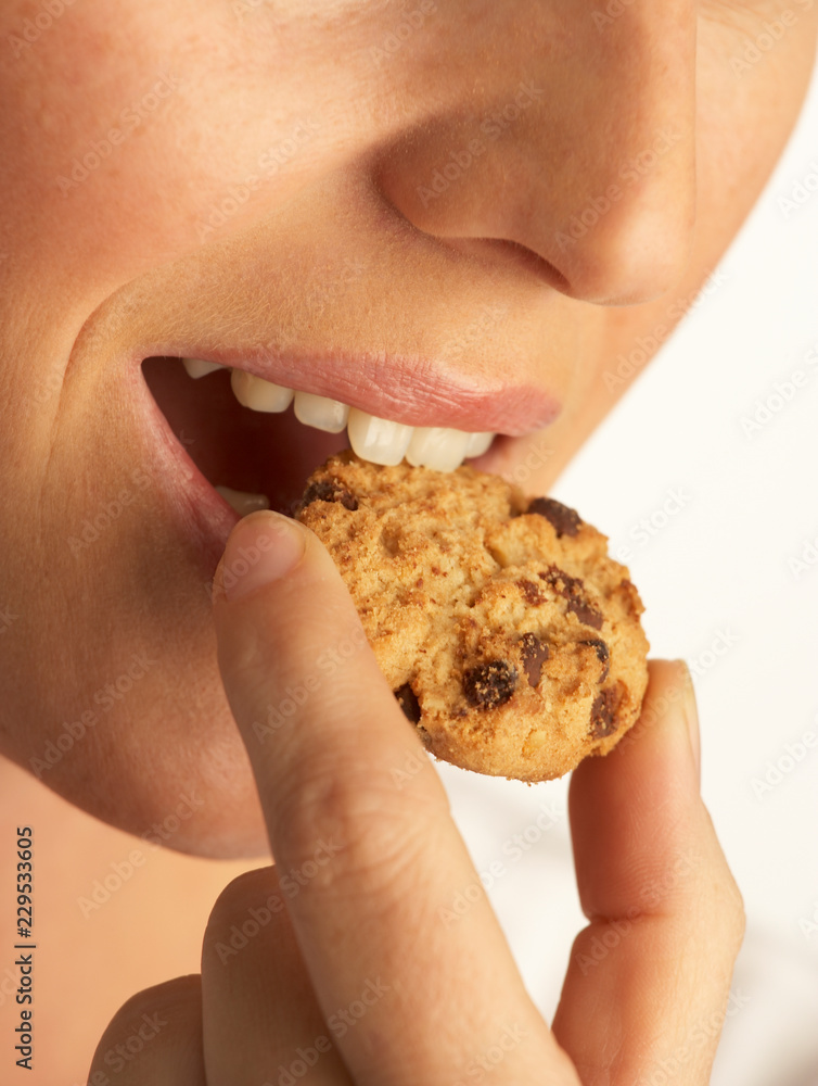 YOUNG WOMAN EATING CHOCOLATE CHIP COOKIE IN CLOSE UP YOUNG WOMAN EATING CHOCOLATE CHIP COOKIE IN CLOSE UP