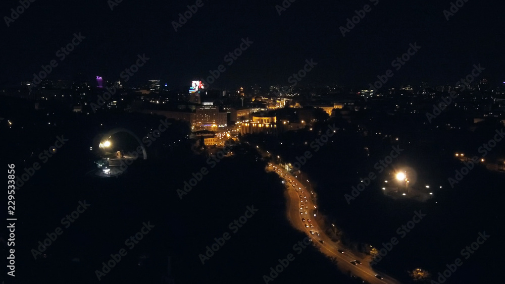Aerial view from Drone: Night city flying over the road and night lights. The movement of cars on the night road.