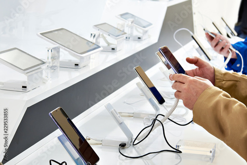 Buyer hands with mobile smartphones in electronics store