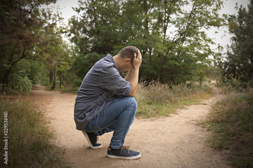 Stressed man sitting at crossroads. Concept of choice