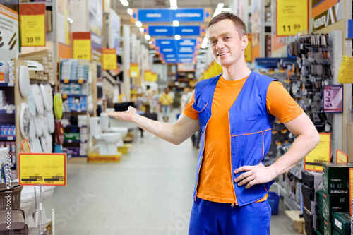 Obraz na plátně salesman at construction super store offers with gesture to visit a store
