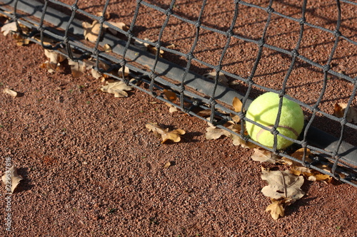 Tennis ball on the court and autumn leaves. © dorotaam