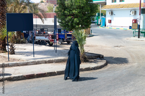 Arabian women in traditional dress walking through the city in Aswan, Egypt photo