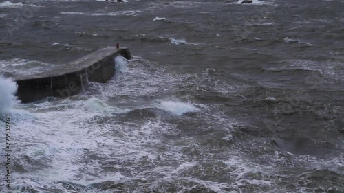 rough stormy waves crashing against a harbour wall in scotland during an autumn stormy afternoon. photo