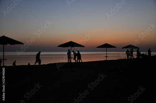 silhouettes of people at sunset on the background of the sea © Баранов Денис