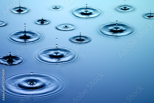 Falling rain - raindrops fall on smooth surface of water photo