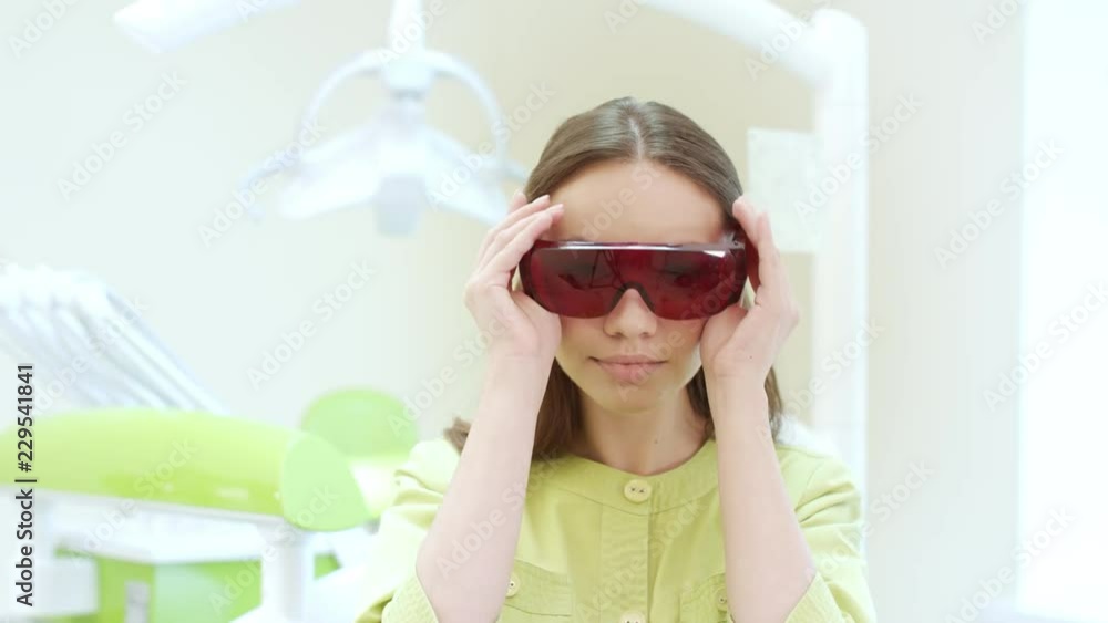 Female dentist dressing up ultraviolet orange safety goggles. Portrait