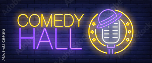 Comedy hall neon sign. Microphone with hat on brick background. Standup show, nightclub, performance. Night bright advertisement. Vector illustration for leisure, nightlife, entertainment