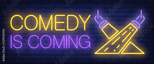 Comedy is coming neon sign. Searchlights on brick background. Standup show, live show, performance. Night bright advertisement. Vector illustration in neon style for leisure, show, entertainment