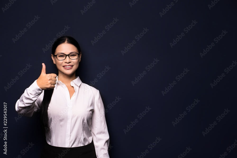 Happy smiling beautiful young business woman showing okay gesture, isolated over dark background Happy smiling beautiful young business woman showing okay gesture, isolated over dark background