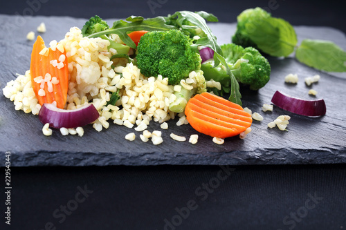 Potrawa w diecie odchudzającej, ryż z brokułami i marchew Ryż brązowy z warzywami podana czarnym talerzu. 