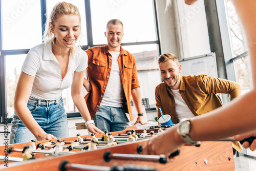 cropped shot of happy casual business people playing table football at office and having fun together