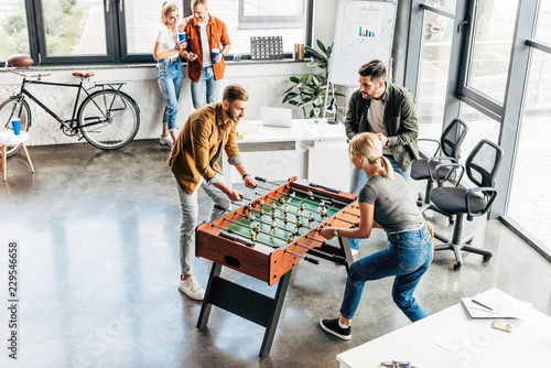 Foto high angle view of young casual business people playing table football at office