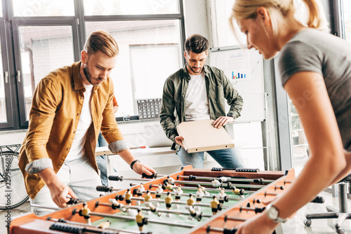 group of happy casual business people playing table football at office and having fun together