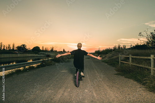 Portrait of a young man with a bmx bicycle. Guy riding a bike in a sunset