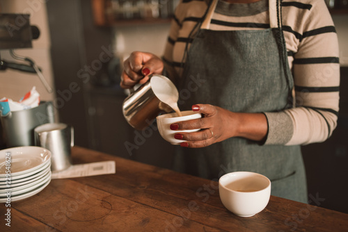 Closeup of an African barista making a cup of cappuccino