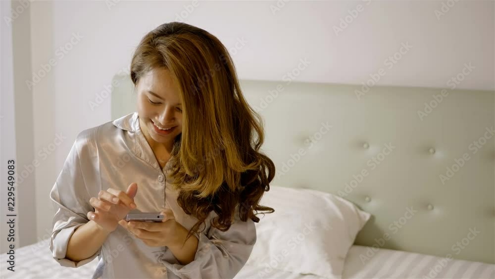 Beautiful asian woman in sleepwear are using the smart phone on the bed in the morning.